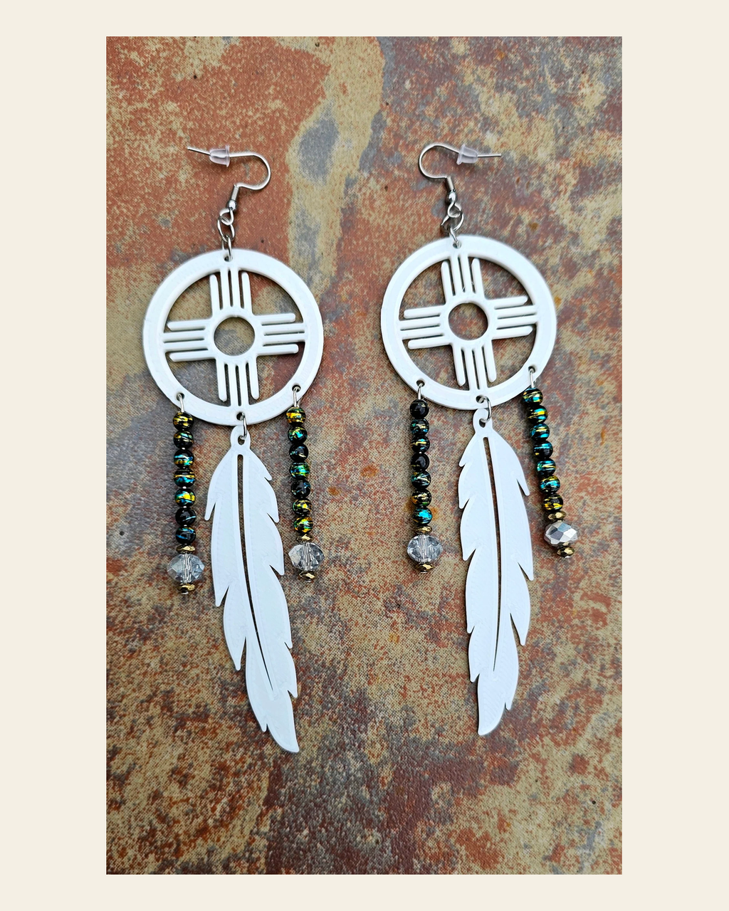 3D print Lightweight New Mexico Zia Feather Dream Catcher Earrings Made in America on a warm cream background