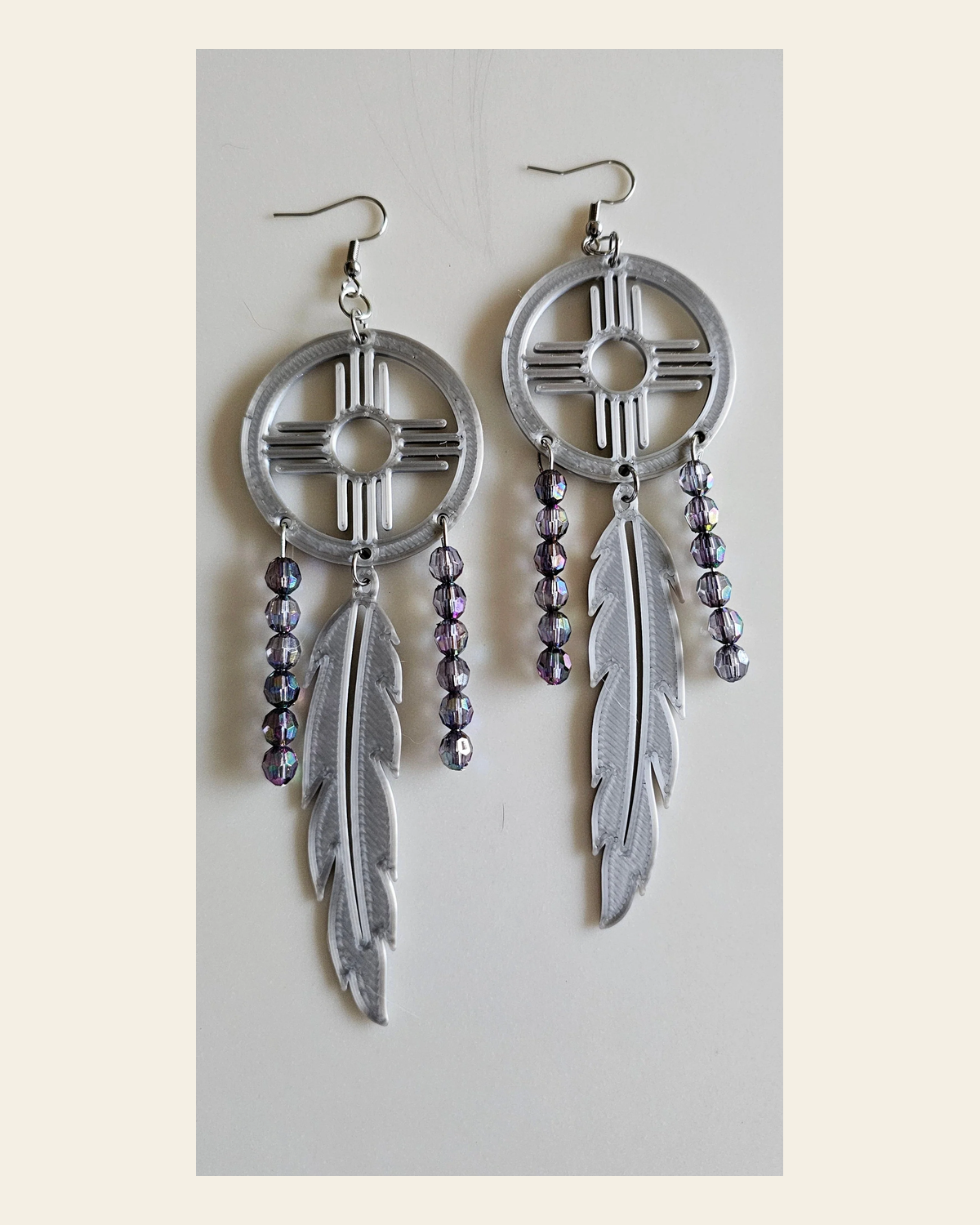 3D print Lightweight Silver New Mexico Zia Feather Dream Catcher Earrings Made in America on a warm cream background