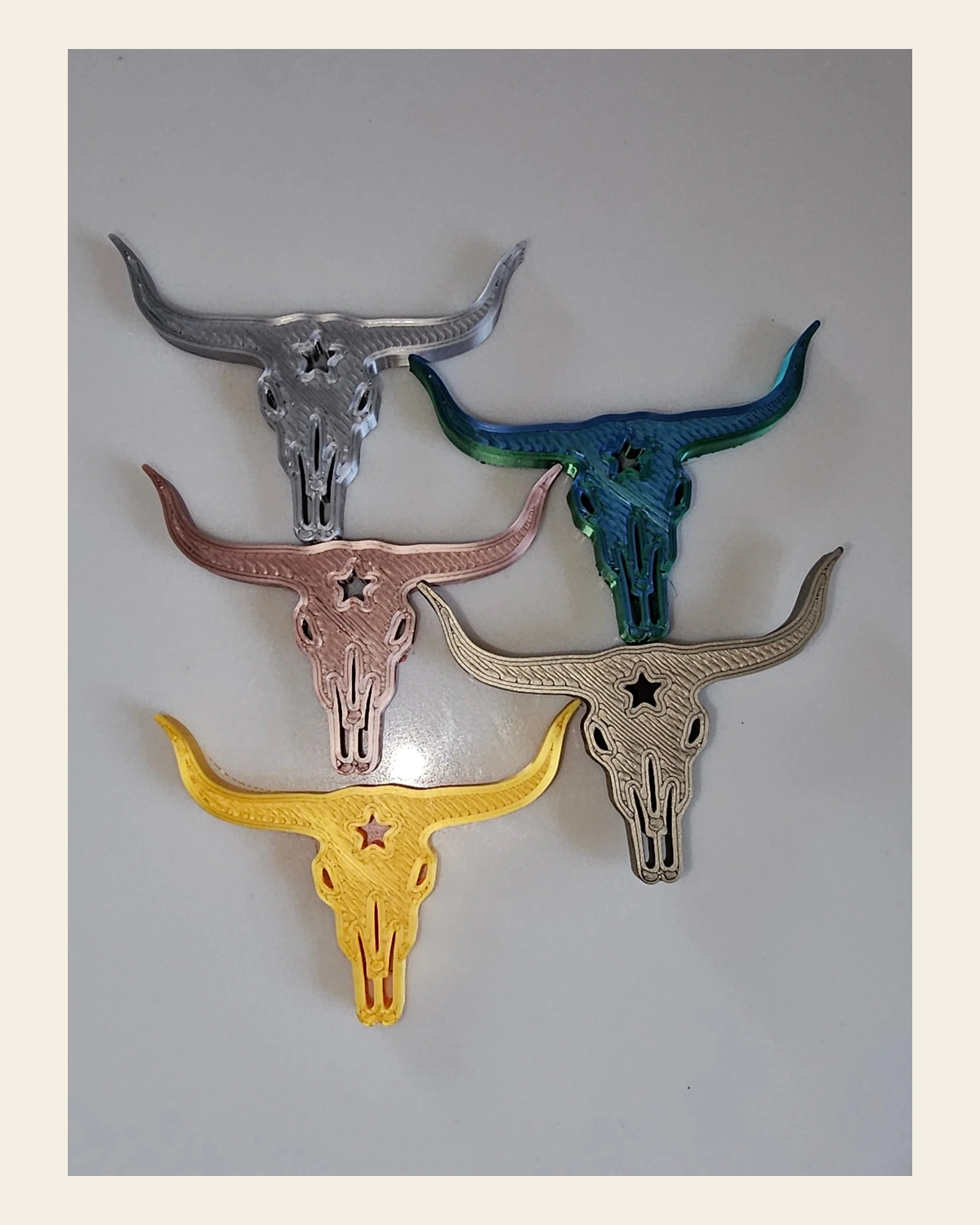 3d Printed Set of 5 Metallic Colors Longhorn Magnets or Pins on a warm cream background