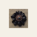 Black Carnation Flower With Copper Jet & Topaz 1" Concho on a warm cream background