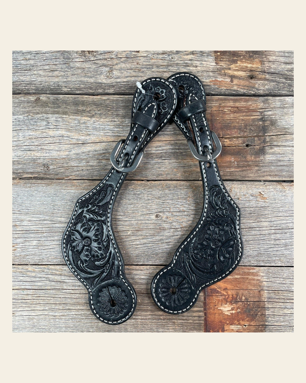 Black Genuine Leather Floral Tooled Spur Straps on a warm cream background