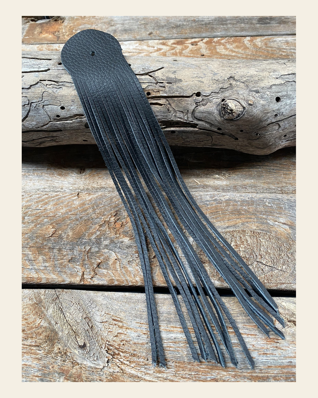 Black Leather Fringe on a warm cream background