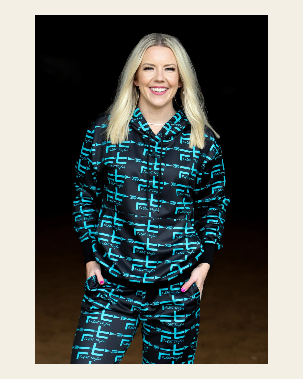 Black & Teal Fallon Taylor Logo Hoodie (adult) on a warm cream background