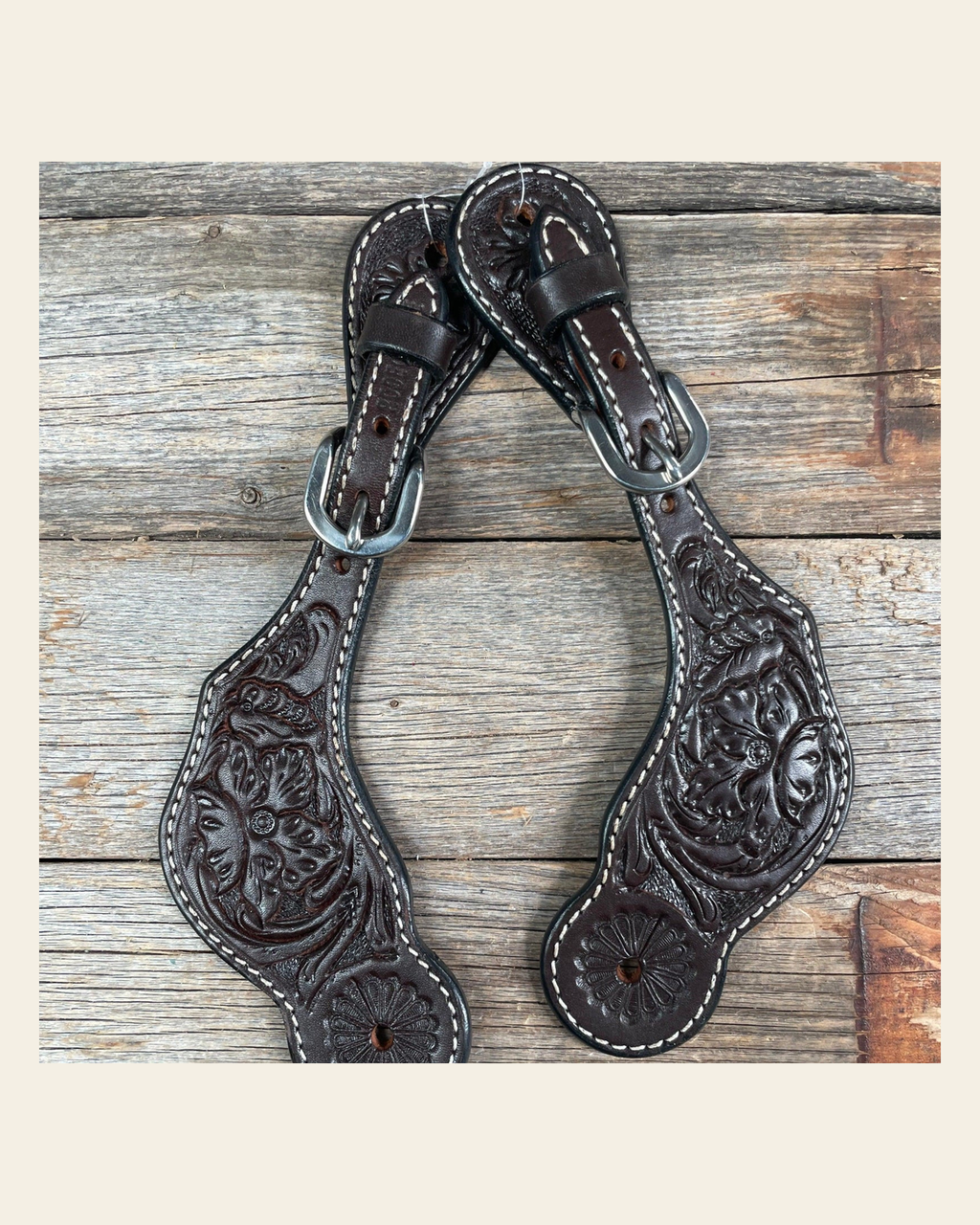 Dark Oil Genuine Leather Floral Tooled Spur Straps on a warm cream background