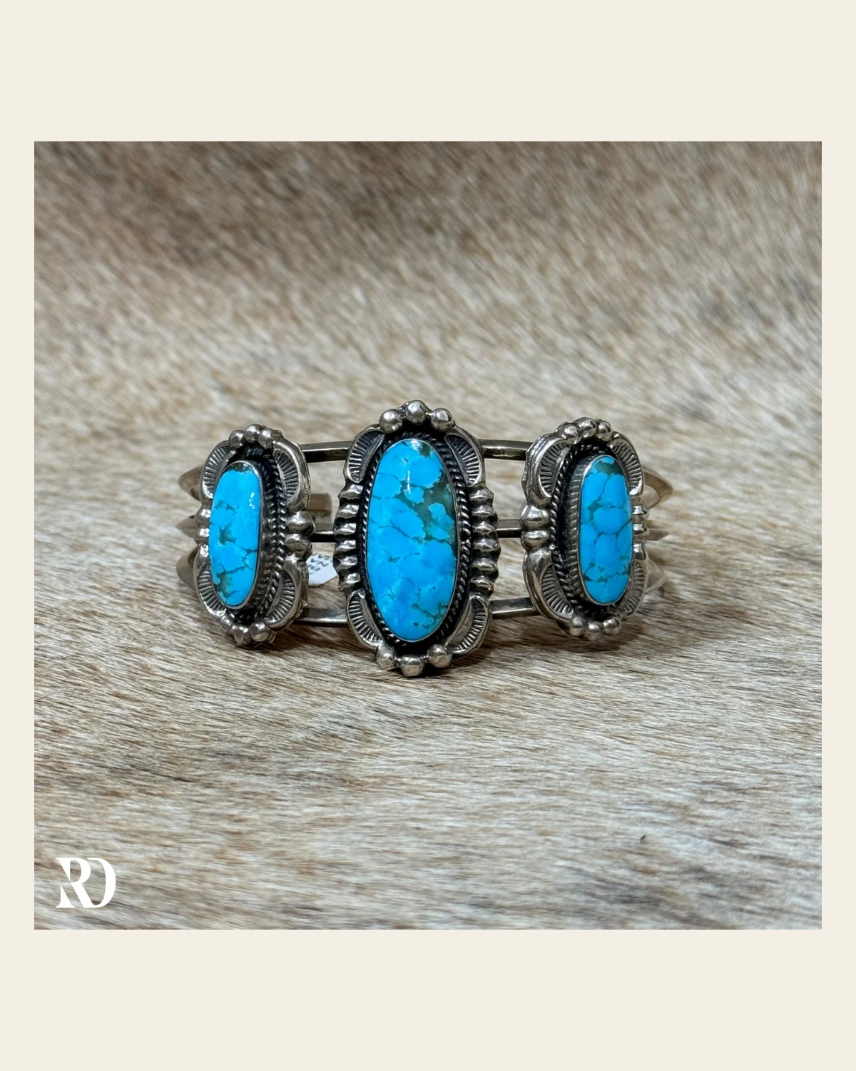 Kingman Three Stone Turquoise Cuff By Amos Begay on a warm cream background