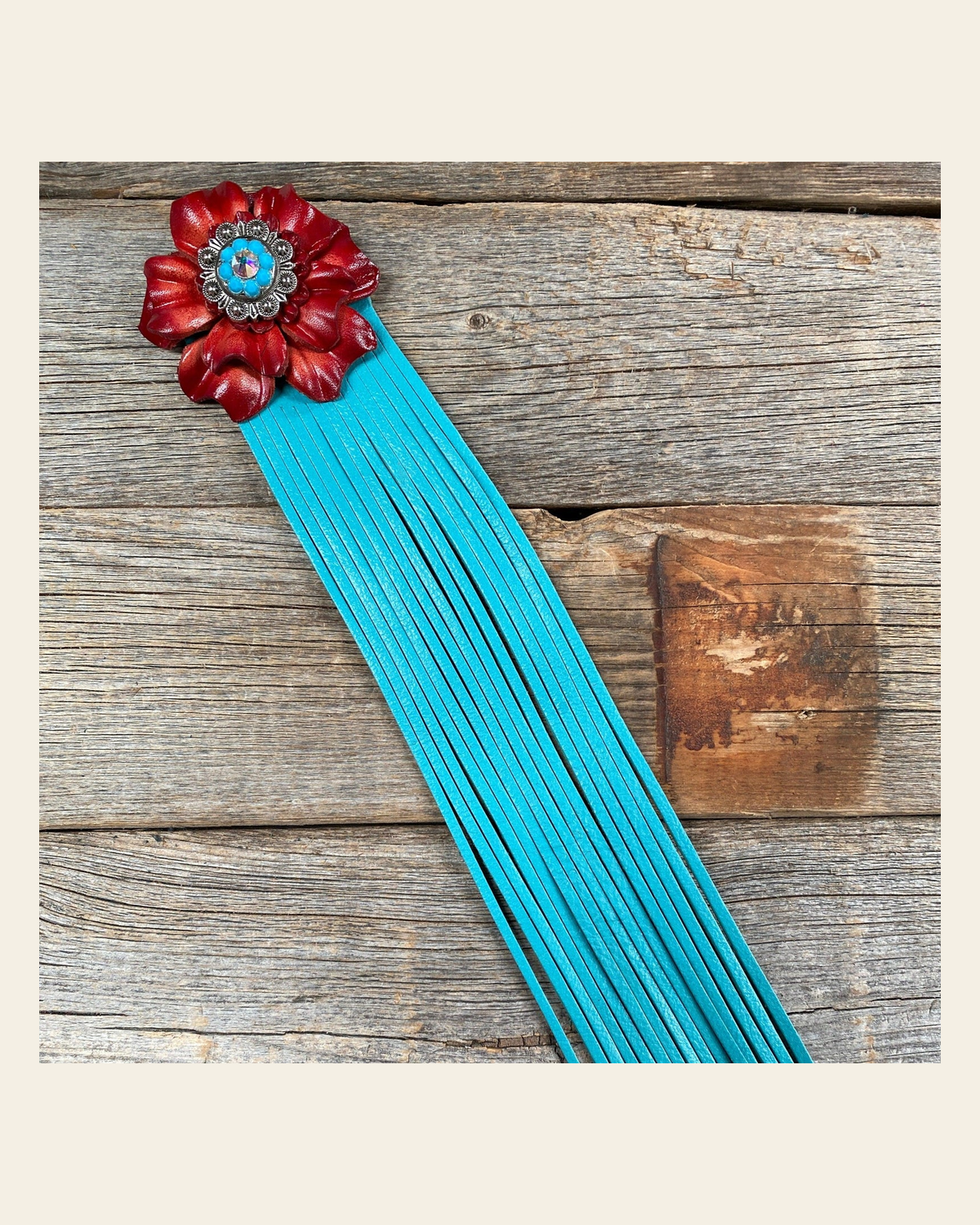 Leather Red Carnation with Turquoise Fringe on a warm cream background