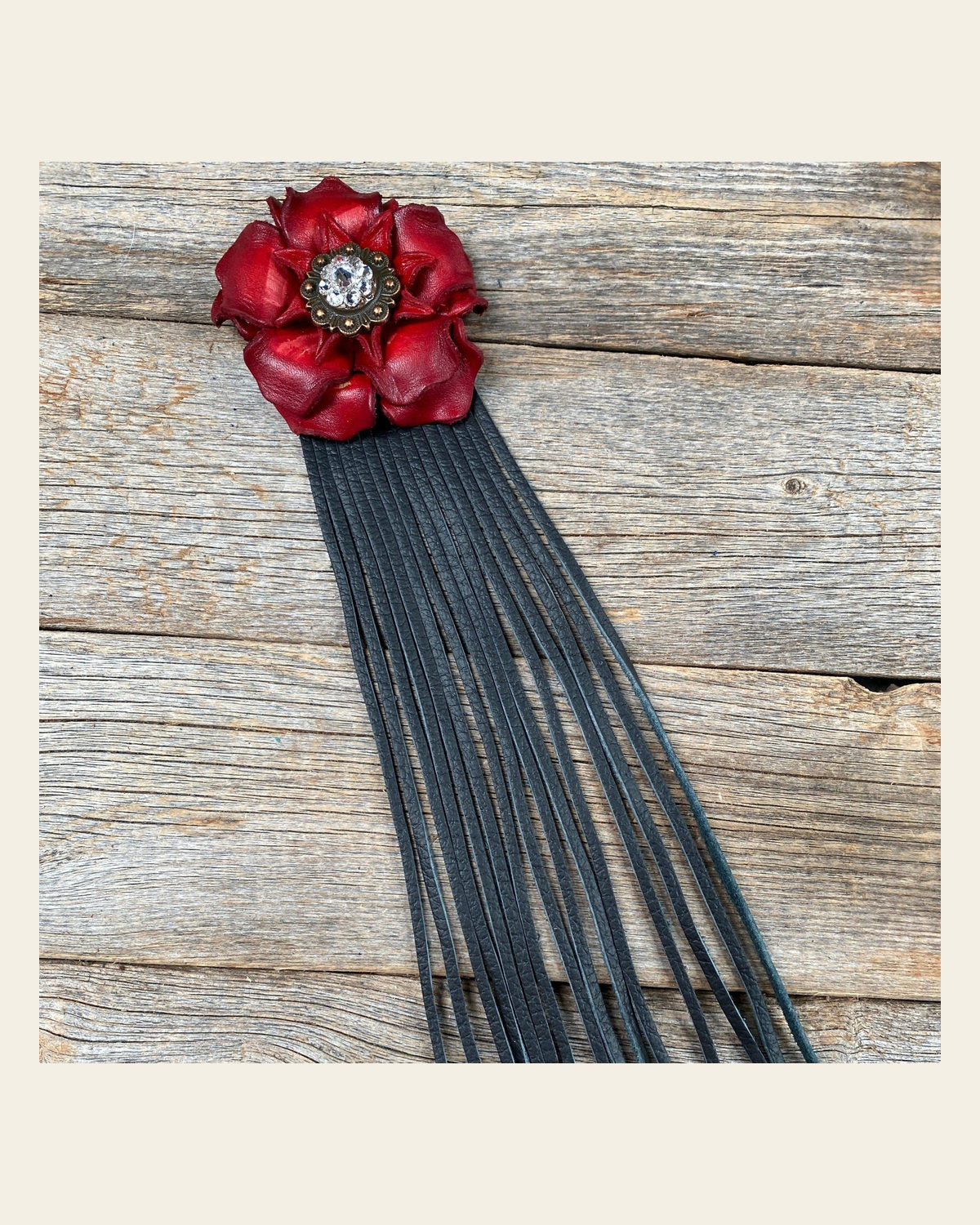 Leather Red Gardenia with Black Fringe on a warm cream background