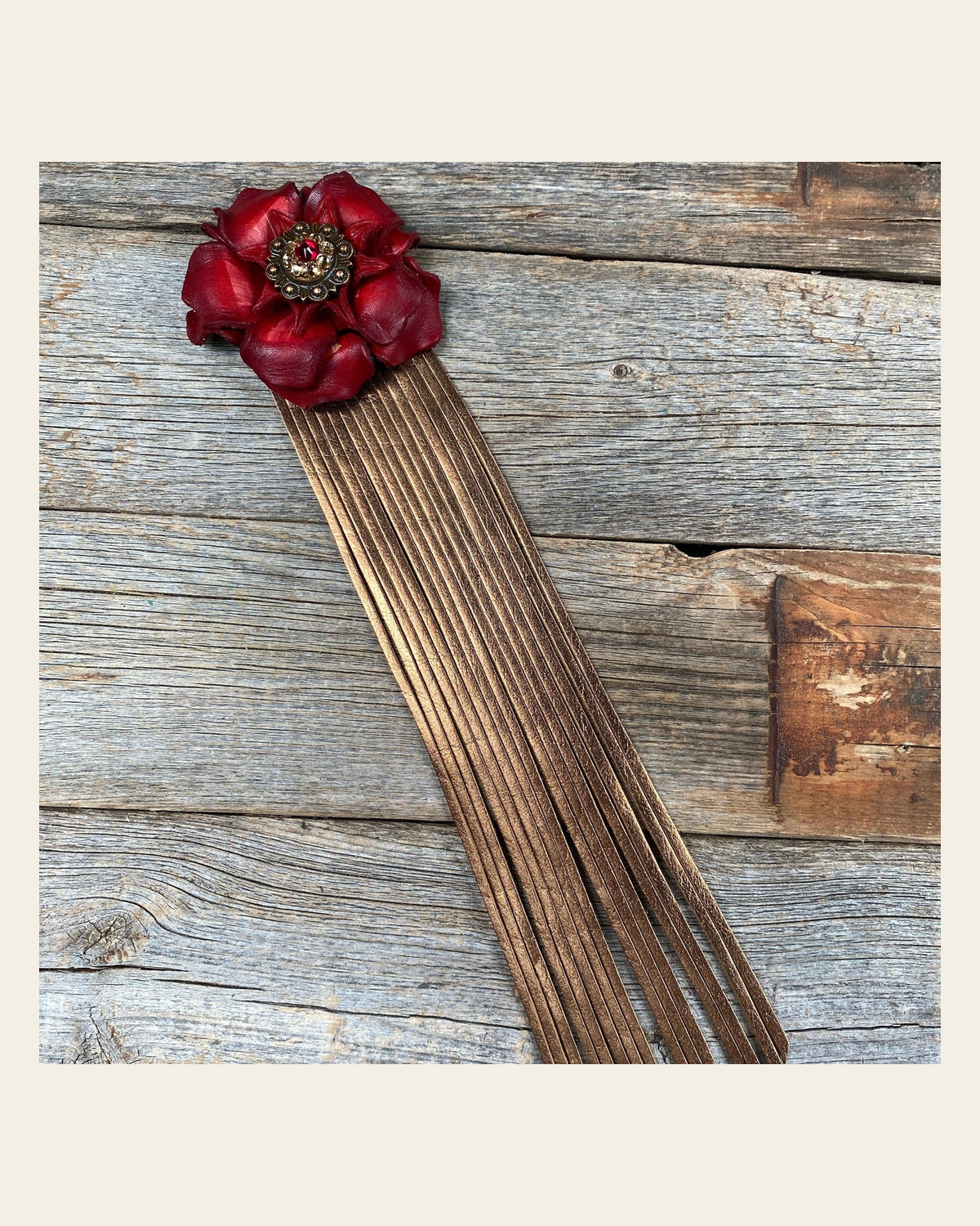 Leather Red Gardenia with Copper Fringe on a warm cream background