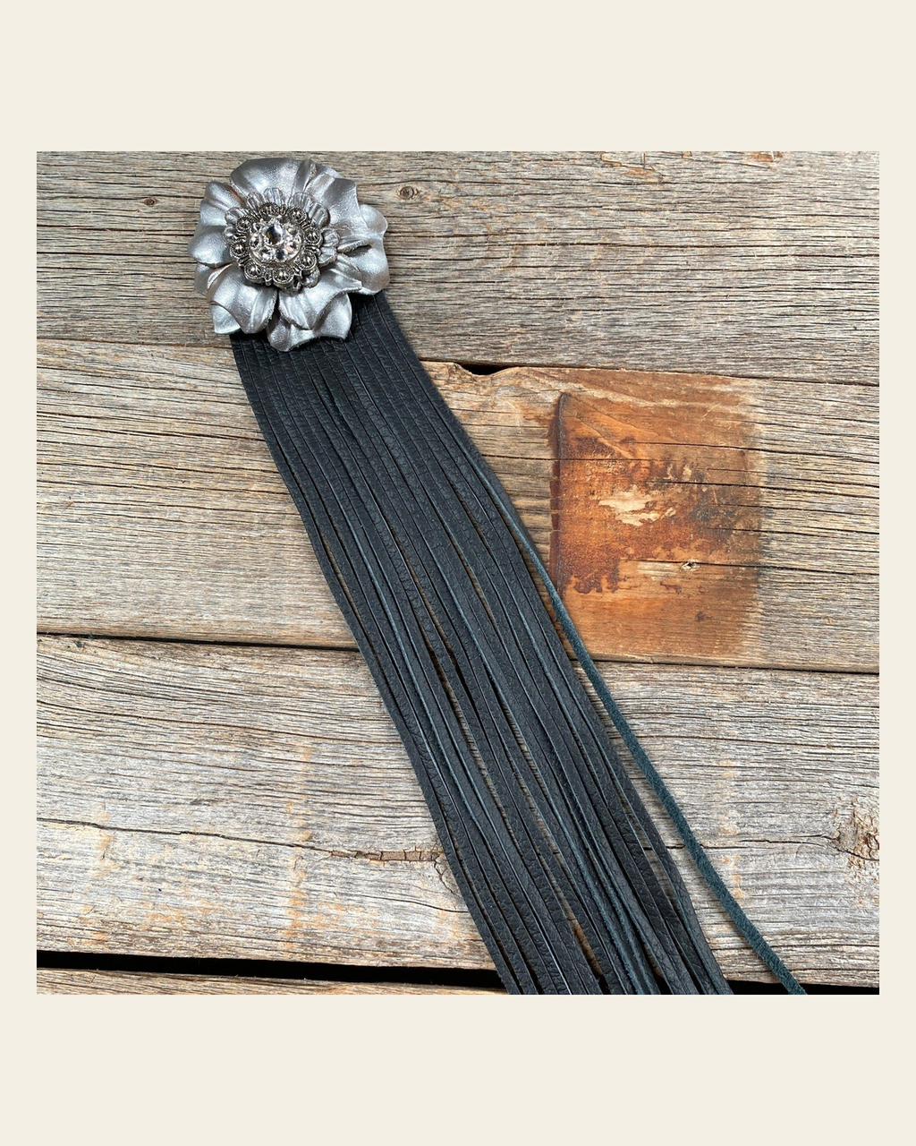 Leather Silver Carnation with Black Fringe on a warm cream background