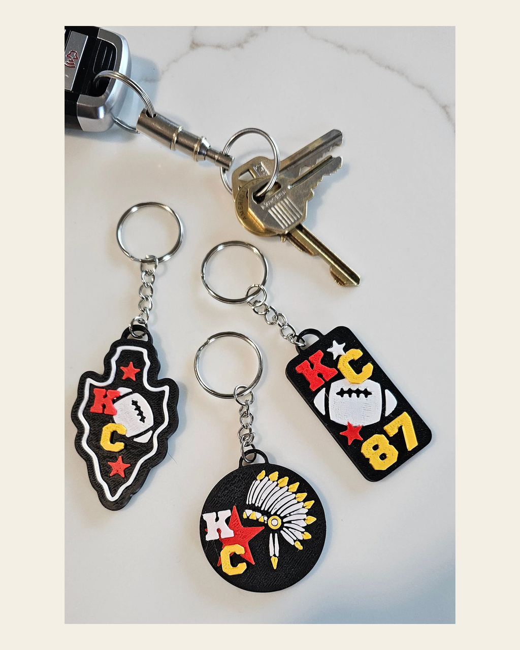 Set of 3 3D Print Chiefs Arrowhead Kc Kansas City 87 Football Keychains Made in America on a warm cream background