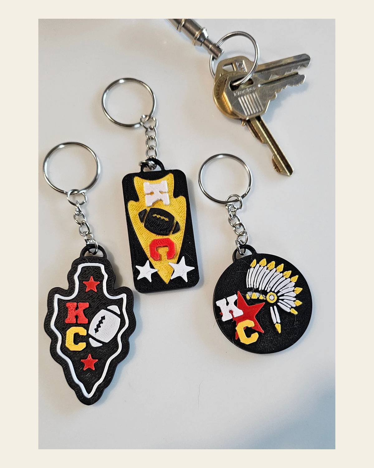 Set of 3 3D Print Chiefs Arrowhead Kc Kansas City Football Keychains Made in America on a warm cream background