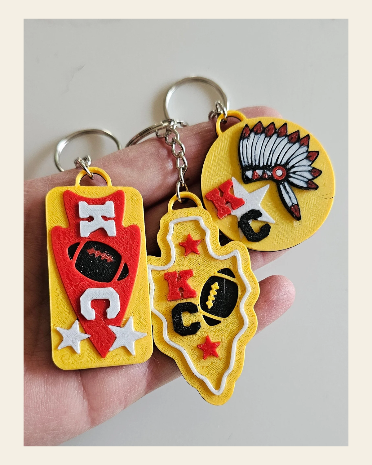 Set of 3 3D Print Chiefs Arrowhead Kc Kansas City Football Keychains Made in America on a warm cream background