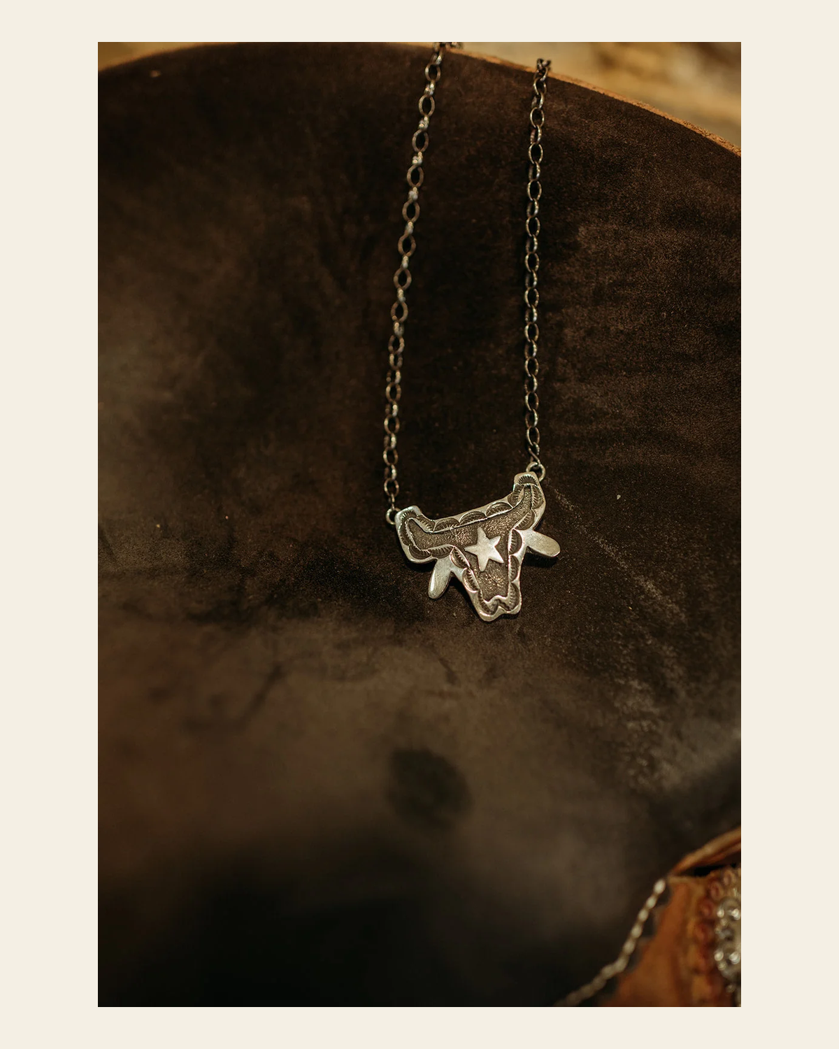 Sterling Silver Bull Skull Necklace By Emerson Kinsel on a warm cream background