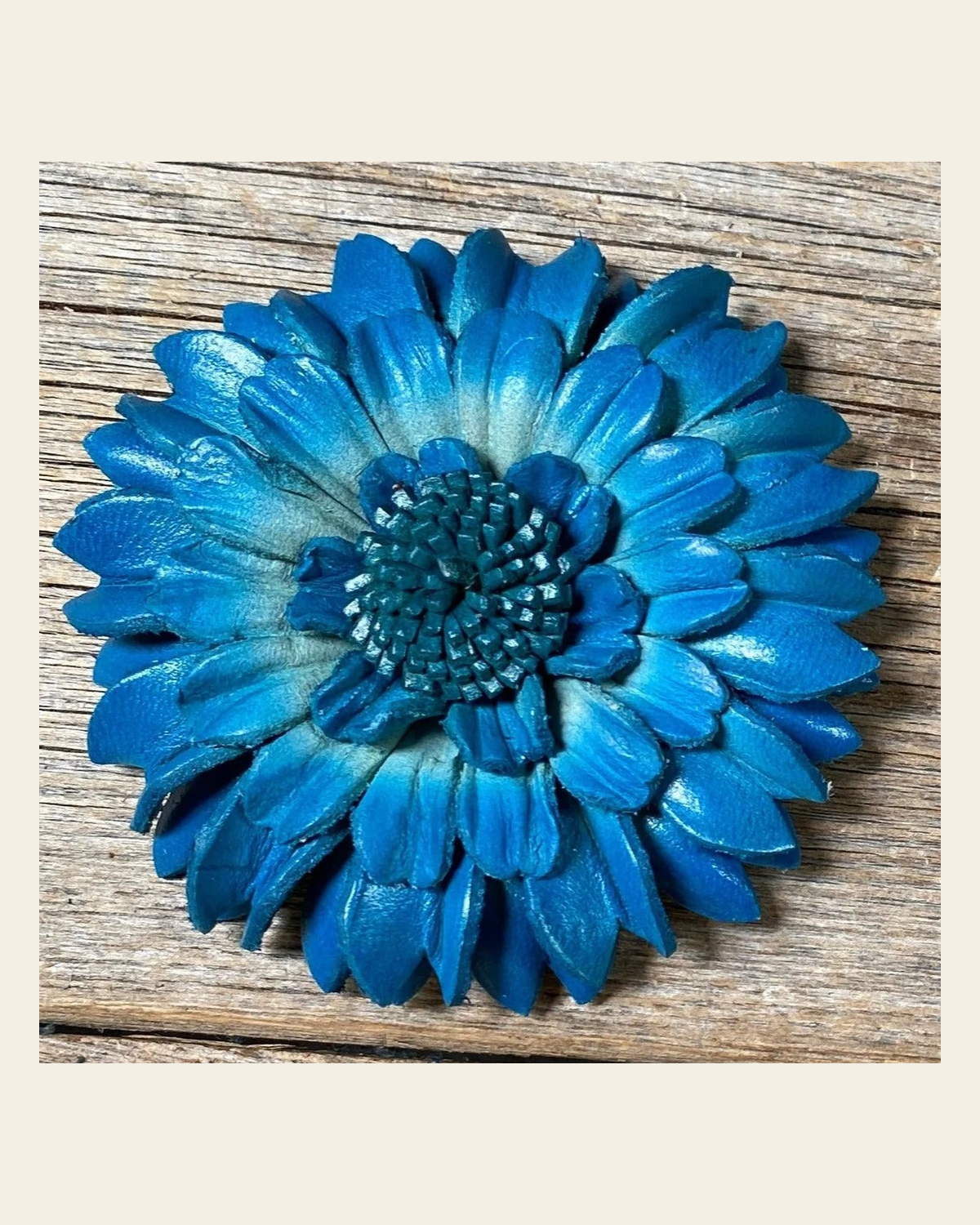 Turquoise Daisy Leather Flower on a warm cream background